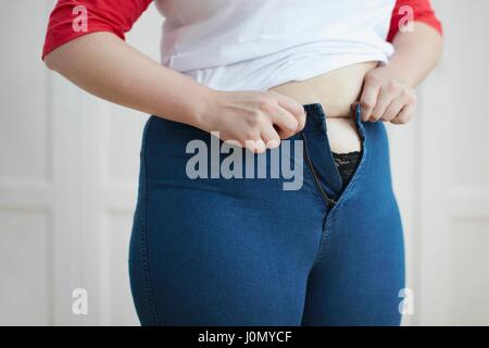 Frau versucht, Schaltfläche "Jeans über Bauch. Stockfoto