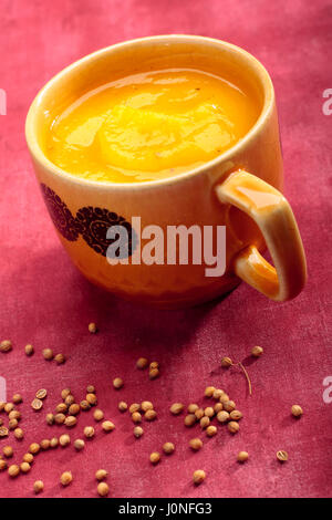 Tasse Kürbis Cremesuppe auf textilen Hintergrund mit Koriandersamen Stockfoto