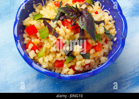 Schale mit Couscous, gehackten Paprika und rotes Basilikum. Draufsicht. Stockfoto