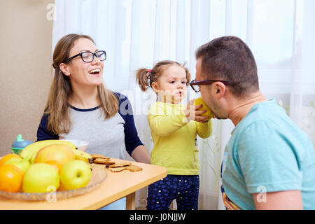 Die Tochter füttert ihr Vater mit einem Apfel in Zimmer Stockfoto