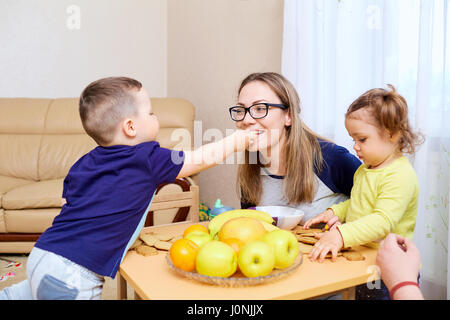 Der Sohn füttert seine Mutter Mama Apple im Zimmer am Tisch Stockfoto