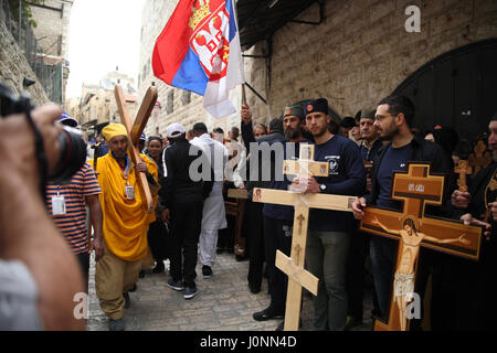 Eine äthiopische Pilger tragen ein einfaches Kreuz gehen von den serbischen Pilgern mit verzierten Holzkreuze warten an der Wand der Via Dolorosa-Gasse. Stockfoto