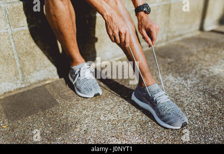 Läufer, die Schnürsenkel, die Vorbereitungen für den Lauf zu binden. selektiven Fokus auf der Seite. Stockfoto