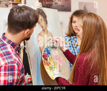 Master-Klasse in der Kunstschule. Der Lehrer zeichnet ein Porträt mit Ölfarben und Schüler den Prozess der Hinrichtung beobachten. Kurse der Zeichnung für Erwachsene Stockfoto