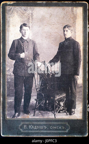 Tambow, Russische Föderation - 29. März 2015 Vintage Foto von zwei jungen Männern stehen in der Nähe von Stuhl im Fotostudio. Foto wurde zu Beginn des 2 Stockfoto
