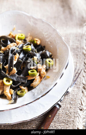 Schwarze Nudeln mit Huhn und leckere grüne Oliven Stockfoto