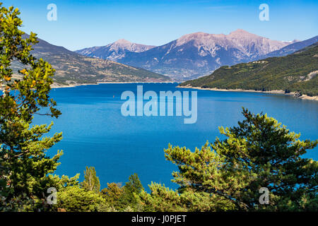 Serre-Ponçon See im Sommer mit der Savines-le-Lac-Brücke in der Ferne. Hautes-Alpes, Region Paca, Souther französische Alpen, Frankreich Stockfoto