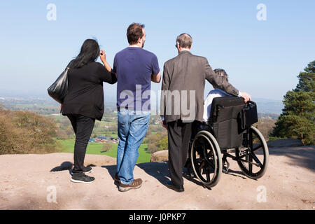 Familie Sightseeing mit einer Person in einem Rollstuhl genießen Sie den Blick / Szene / Landschaft in Cheshire Plain / Flachland tagsüber, an Alderley Edge, UK. Stockfoto