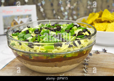 Mexikanische sieben Schicht Dip - Guacamole, Käse, Frühlingszwiebeln, Oliven, rote Bohnen, weiße Bohnen paste Stockfoto