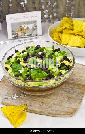 Mexikanische sieben Schicht Dip - Guacamole, Käse, Frühlingszwiebeln, Oliven, rote Bohnen, weiße Bohnen paste Stockfoto