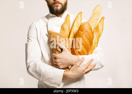 Brot in der hand. Frisch gebackenes Brot in den Händen. Mann mit Bart mit viel Brot in Hand isoliert auf weißem Hintergrund. Stockfoto