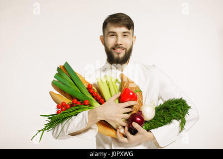 Lächeln auf den Lippen schön Koch mit Gemüse in Händen isoliert auf weißem Hintergrund. VEGANES ESSEN. Stockfoto