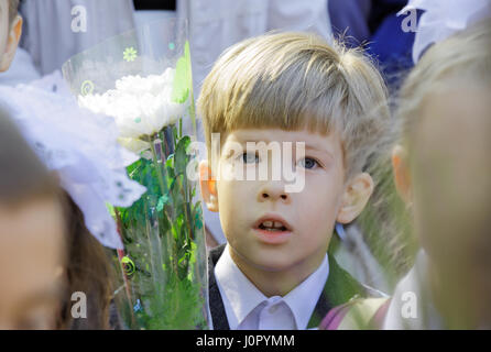 Ein verwirrt zuerst-Grader in einer Schule-Linie mit einem Blumenstrauß Stockfoto