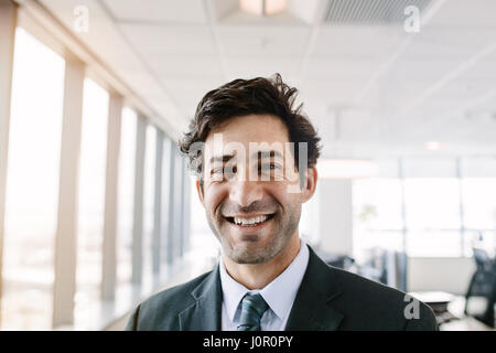 Porträt der erfolgreiche Jungunternehmer im Büro stehen. Manager im Anzug, Blick in die Kamera mit einem Lächeln. Stockfoto