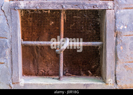 alte Fenster in das Gebäude mit Traversen auf dem Fenster, unwillkommene Einmischung zu vermeiden Stockfoto