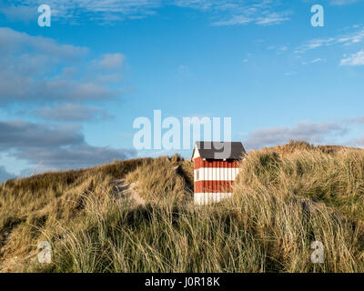 Kleine rot-weiß gestreiften Hütte stehend auf den Strand Dünen mit Blick aufs Meer Stockfoto