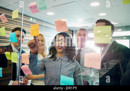 Geschäftsleute im Büro an der Wand mit den Aufklebern zusammen. Mixed Team von Unternehmern Stockfoto