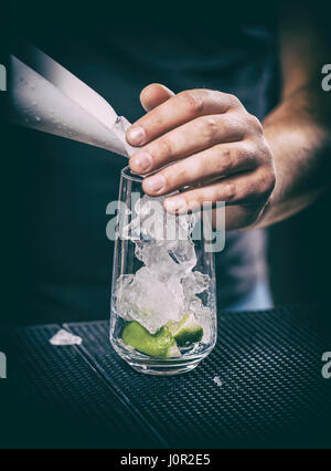 Barkeeper, die Eiswürfel in ein Glas setzen Stockfoto