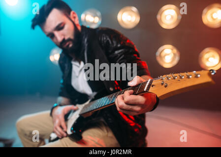 Männliche Solo-Musiker mit Elektro-Gitarre auf der Bühne mit den Dekorationen der Lichter. Musikalische Unterhaltung. Stockfoto