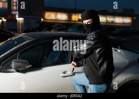 Männliche Auto Dieb Händen versucht, Tür mit Jemmy zu öffnen. Carjacker öffnen Fahrzeug mit Brecheisen auf dem Parkplatz. Carjacking Gefahr. Auto-Diebstahl-Vandalismus Stockfoto