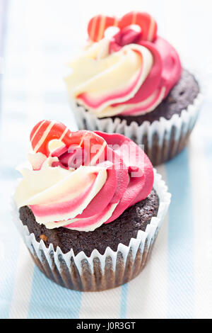 Chocolate Cupcake mit Himbeere-Vanille Glasur und herzförmige Dekoration Stockfoto
