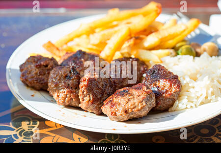 Lamm Kofta mit Reis, Pommes Frites, Oliven auf weiße Platte im Marokkanischen Restaurant Stockfoto