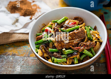 Wok gebratene Rindfleisch, grüne Bohnen, Pilze mit Reisnudeln Stockfoto