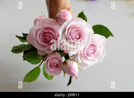 Wunderbare Ton Kunst, Frau Hand halten Strauß Rosen Blumen in Rosa auf weißem Hintergrund, schöne künstliche Blumen von Handwerkskunst mit geschickten Stockfoto