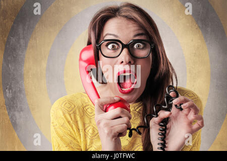 Brünette Frau mit roten Retro-Telefon telefonieren überrascht Stockfoto