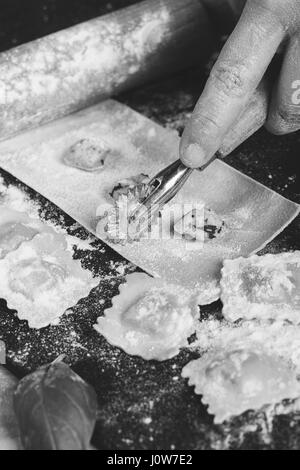 Ravioli in der Küche mit Werkzeugen und Zutaten Zubereitung: Teig, Mehl, Eiern, Füllung, Cutter, Walze, Board. Stockfoto