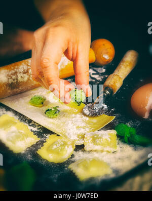 Ravioli in der Küche mit Werkzeugen und Zutaten Zubereitung: Teig, Mehl, Eiern, Füllung, Cutter, Walze, Board. Stockfoto