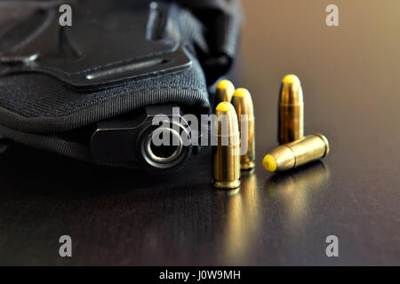 Pistole in schwarze Holster und Kugeln auf dunklen Tisch Stockfoto