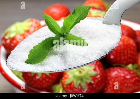 Emaille Löffel mit Stevia über eine Schale mit Erdbeeren auf hölzernen Hintergrund Stockfoto