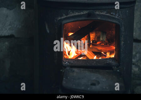 Feuer brennt in schwarzen eisernen Ofen. Nahaufnahme Foto mit selektiven Fokus Stockfoto