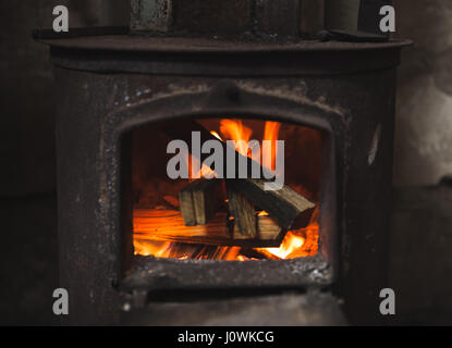 Feuer im kleinen schwarzen Ofen brennt. Nahaufnahme Foto mit selektiven Fokus Stockfoto