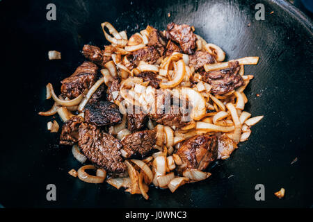 Plov im Kessel kochen. Nur Fleisch und Zwiebeln in einem Kessel. Feldküche. Küche des Ostens. Stockfoto
