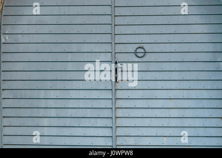 Ein blau-grau Metall Tor in einer Steinmauer. Struktur aus Metall. Stockfoto