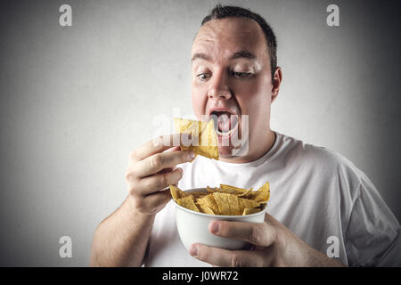 Mann isst Chips im Inneren Stockfoto