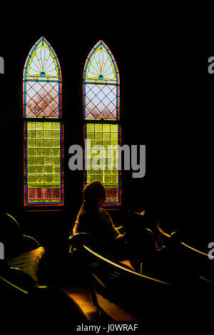 Ein senior Mann sitzt in der Kirche unter Glasfenster seiner Bibellektüre in White River Junction, Vermont, USA. Stockfoto