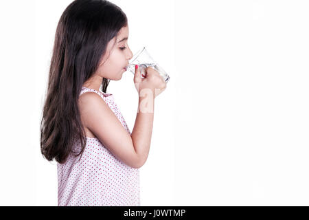 Schöne glückliche kleine Mädchen mit lange dunkle Haare und Kleid mit Glas Wasser. Seitenansicht und trinken Wasser mit geschlossenen Augen. Studioaufnahme, isoliert auf Stockfoto