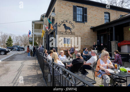 Kunden sitzen an Tischen auf der Außenterrasse im schwarzen Hund Dorf Pub & Bistro, Bar, Pub, Restaurant im Dorf Bayfield, Ontario. Stockfoto