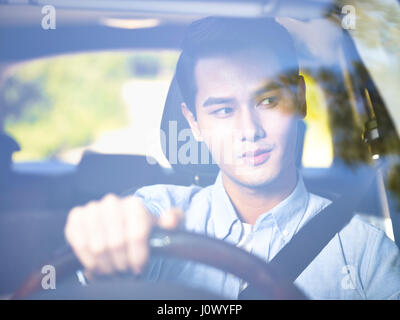 junge asiatische Mann Autofahren durch die Windschutzscheibe sehen. Stockfoto