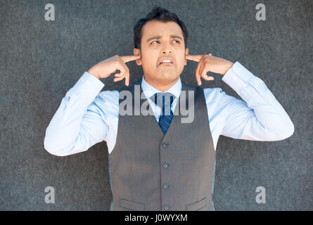 Closeup Portrait, wütend unglücklich betonte Mann in Weste und Krawatte, Abdeckung geschlossen Ohren auf der Suche nach oben, dass laute Geräusche, es ist mir Kopfschmerzen, isolieren Stockfoto
