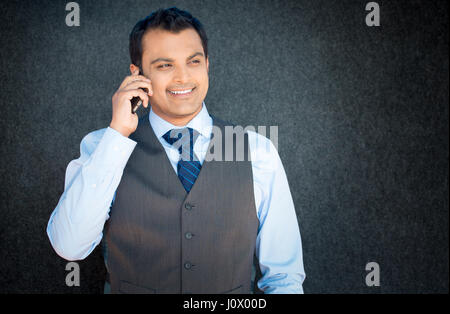 Closeup Portrait, hübscher junger Geschäftsmann, glücklicher Kerl, Weste und Krawatte, mit Handy, lächelnd, isoliert angenehmes Gespräch, grau blac Stockfoto