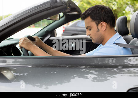 Closeup Portrait müde schönen jungen Mann mit kurzen Aufmerksamkeitsspanne, mit seinem Auto nach langen Stunden Reise, am Steuer, wach zu bleiben versuchen Ou isoliert Stockfoto