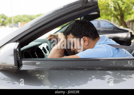 Closeup Portrait müde schönen jungen Mann mit kurzen Aufmerksamkeitsspanne, mit seinem Auto nach langen Stunden Reise, am Steuer, wach zu bleiben versuchen Ou isoliert Stockfoto