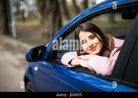 Hübsche junge Frau sitzt im Auto unterwegs Stockfoto