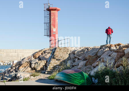 Ein Mann mit einem roten Anorak Blick in den Hafen von Carboneras, Provinz Almería, Spanien. Stockfoto