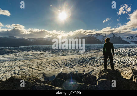 Mann steht auf dem Stein über Grey Gletscher in Patagonien bei Sonnenuntergang mit Sonne Stockfoto