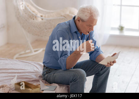 Ernsthafte nachdenklicher Mann beißt seine Brille Stockfoto